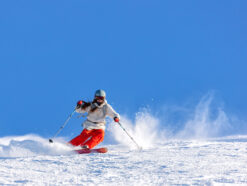 Girl skier in a white jacket and red pants
